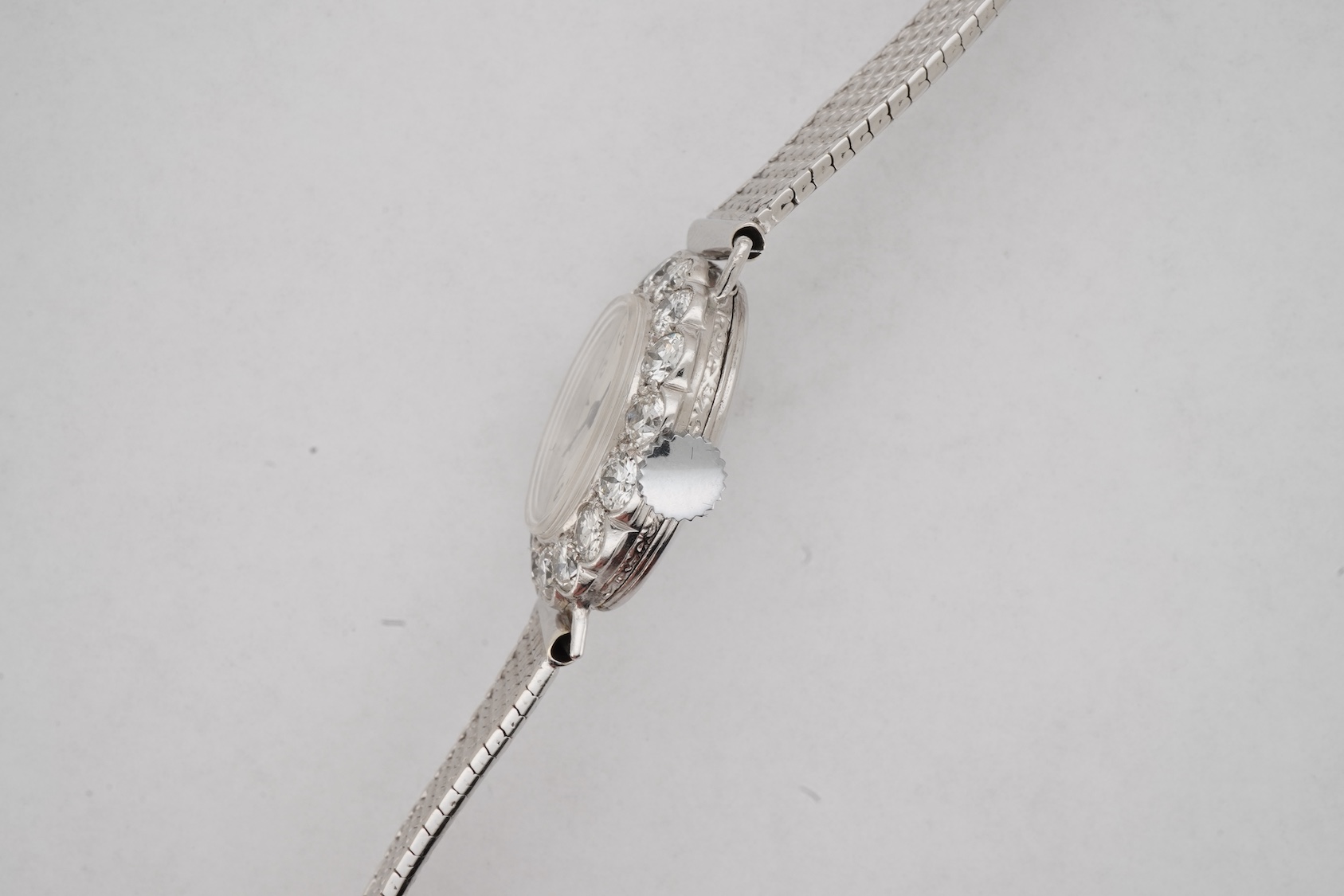 A lady's early 1940's platinum and diamond set manual wind cocktail watch, on a 9ct white gold mesh link bracelet